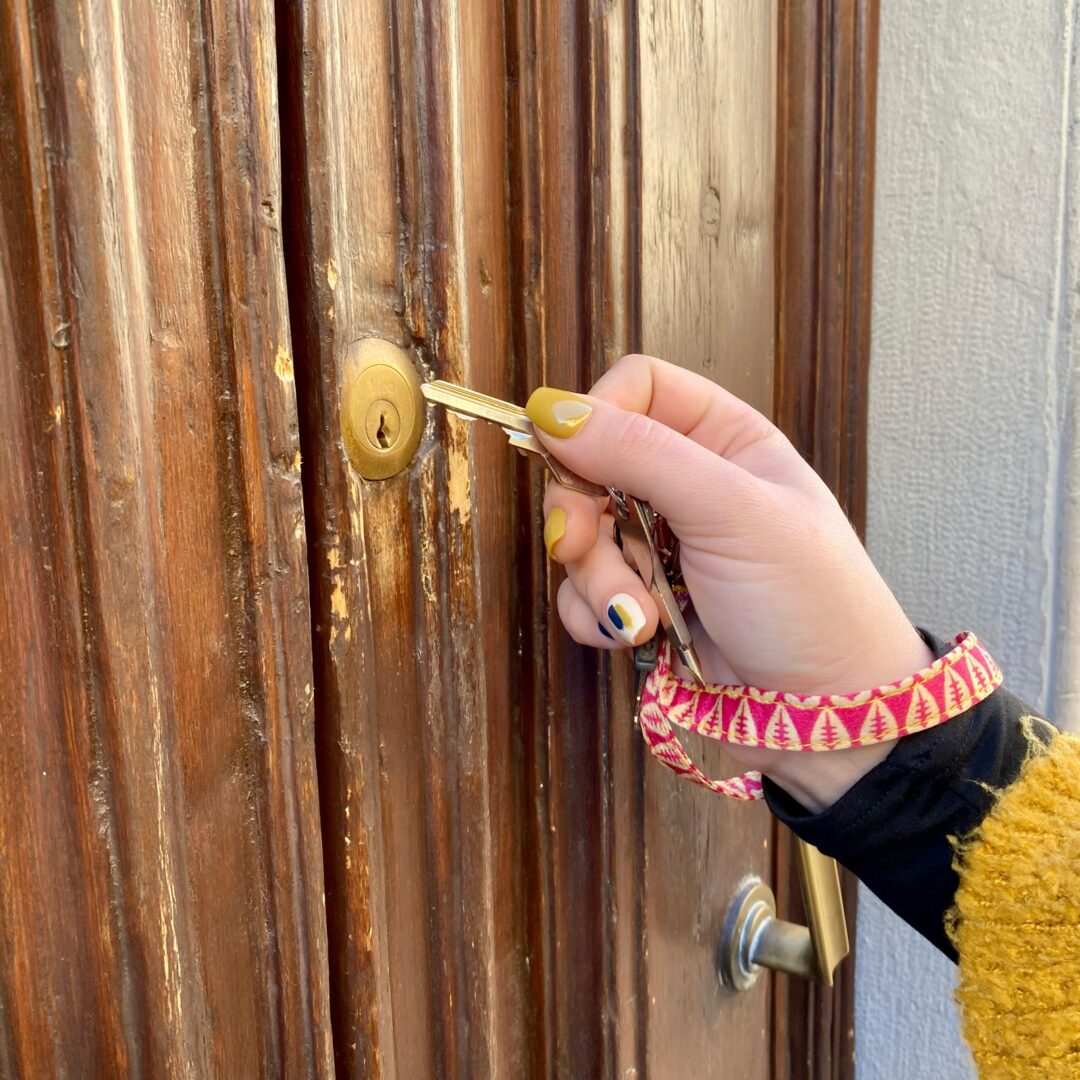 Foto esemplificativa dell'uso del cordino con moschettone da polso come portachiavi davanti ad un portone